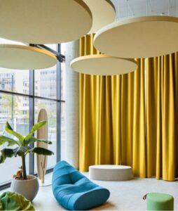 Aménagement acoustique intérieur avec rideaux jaunes absorbants et mobilier confortable pour espace de réunion professionnel par IRIS Connect