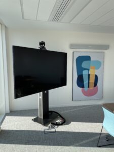 Salle de réunion professionnelle avec deux écrans de visioconférence affichant des participants et équipée d'une caméra Aver, d'une barre micro nureva, d'une table ronde et chaise grise