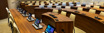 Salle de conférence équipée de pupitres modernes avec écrans et microphones pour délibérations, réunions officielles et assemblées consultatives.
