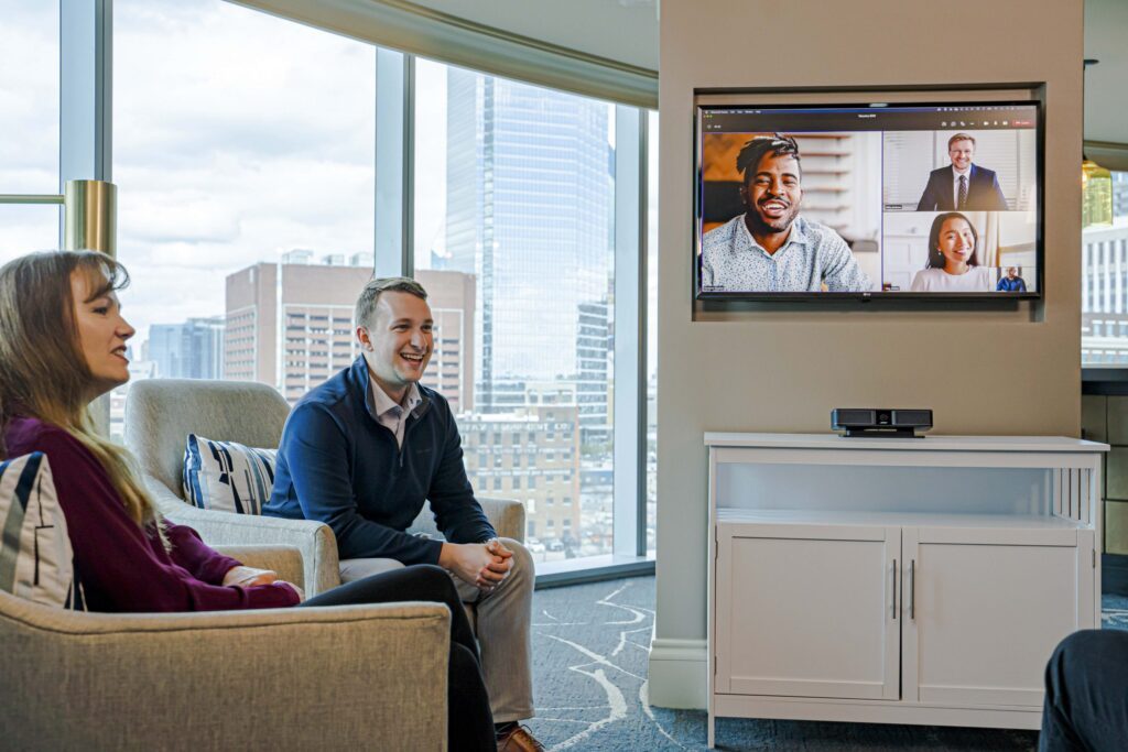 Bose Videobar VB-S en situation de visioconférence dans une salle de réunion moderne avec vue panoramique, professionnels participant à une réunion hybride avec participants distants