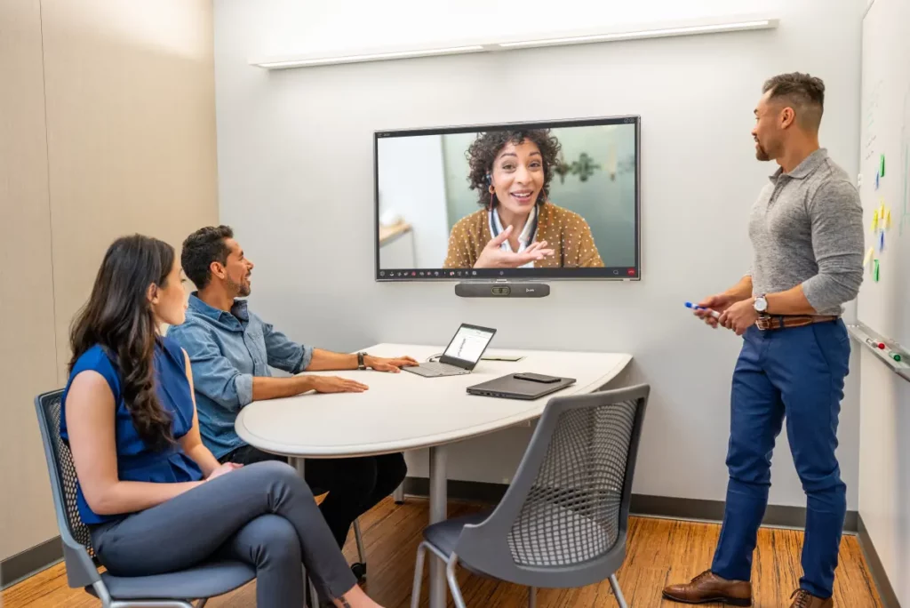 Réunion professionnelle avec système de visioconférence Poly Studio R30 en action, équipe diverse collaborant dans une salle de conférence moderne