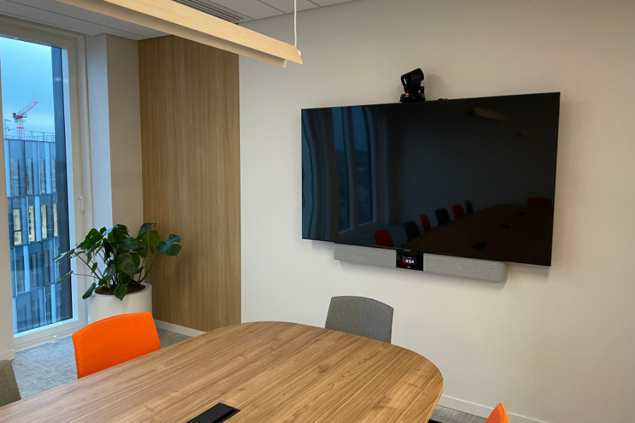 Salle de réunion moderne équipée d'une caméra de visioconférence professionnelle, grand écran et système audio, illustration pour un guide du décideur.