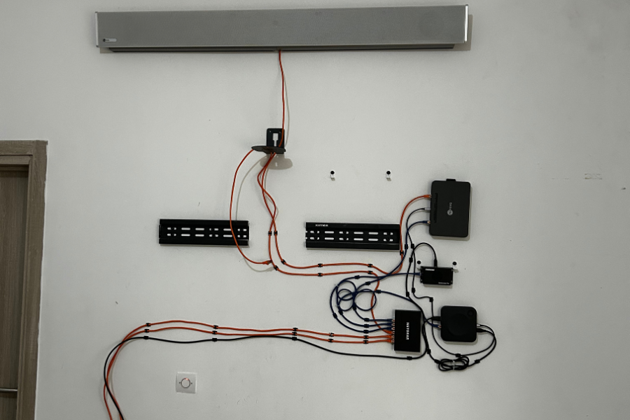 Installation murale désordonnée d'un système de visioconférence avec câbles apparents et multiples boîtiers, illustrant l'importance du choix d'un partenaire expert.