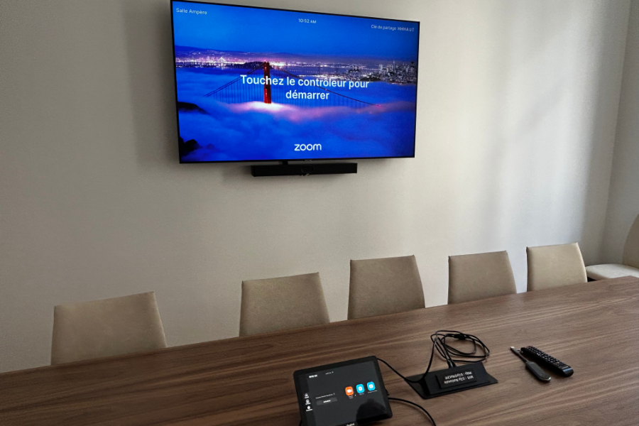 Salle de réunion moderne équipée pour la visioconférence 2025 avec écran mural, barre vidéo et tablette de contrôle, illustrant les bons choix techniques pour le matériel audiovisuel. équipement salle réunion; salle réunion petit budget; Yealink A40; visioconférence