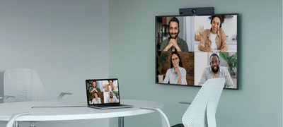 Petite salle de réunion moderne équipée d'un système de visioconférence IRIS Connect, avec un grand écran montrant une réunion en cours.
