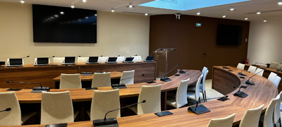 Salle du conseil ou auditorium équipé d'un système de visioconférence et de présentation IRIS Connect, conçu pour les assemblées officielles et les prises de décision.