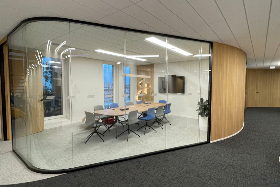 Salle de réunion moderne et lumineuse équipée d'une solution de visioconférence complète, avec grand écran mural et table de conférence, illustrant la transformation des espaces de travail.