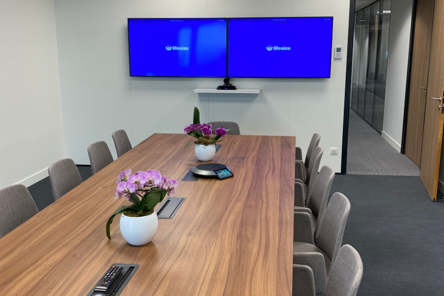 Salle de réunion moderne avec système de visioconférence professionnel, deux écrans et table de conférence, illustrant un équipement adapté aux besoins des entreprises.