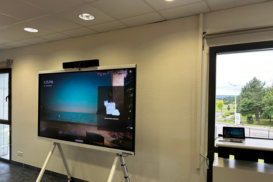 Collaboration professionnelle optimisée grâce à la technologie Barco ClickShare permettant l'affichage simultané de données analytiques et de participants à distance sur système double écran.